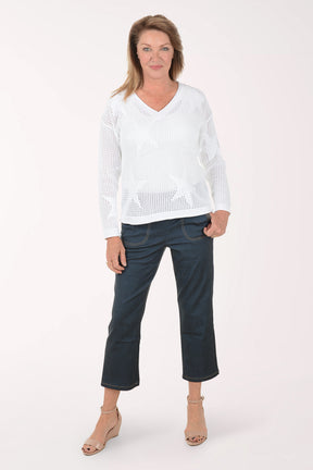 Woman wearing a white sweater and dark blue jeans on a white background