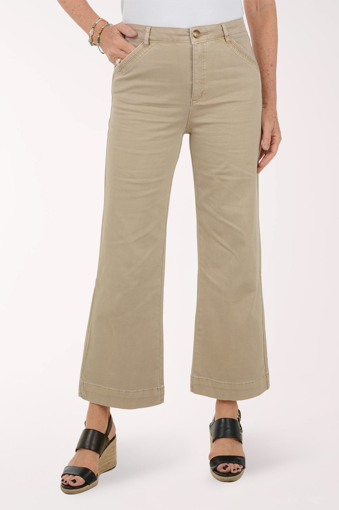 Person wearing beige wide-leg pants on a white background