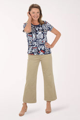 Woman wearing a patterned top and beige pants on a white background