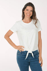 Woman wearing a white t-shirt with a tie detail and blue jeans on a white background