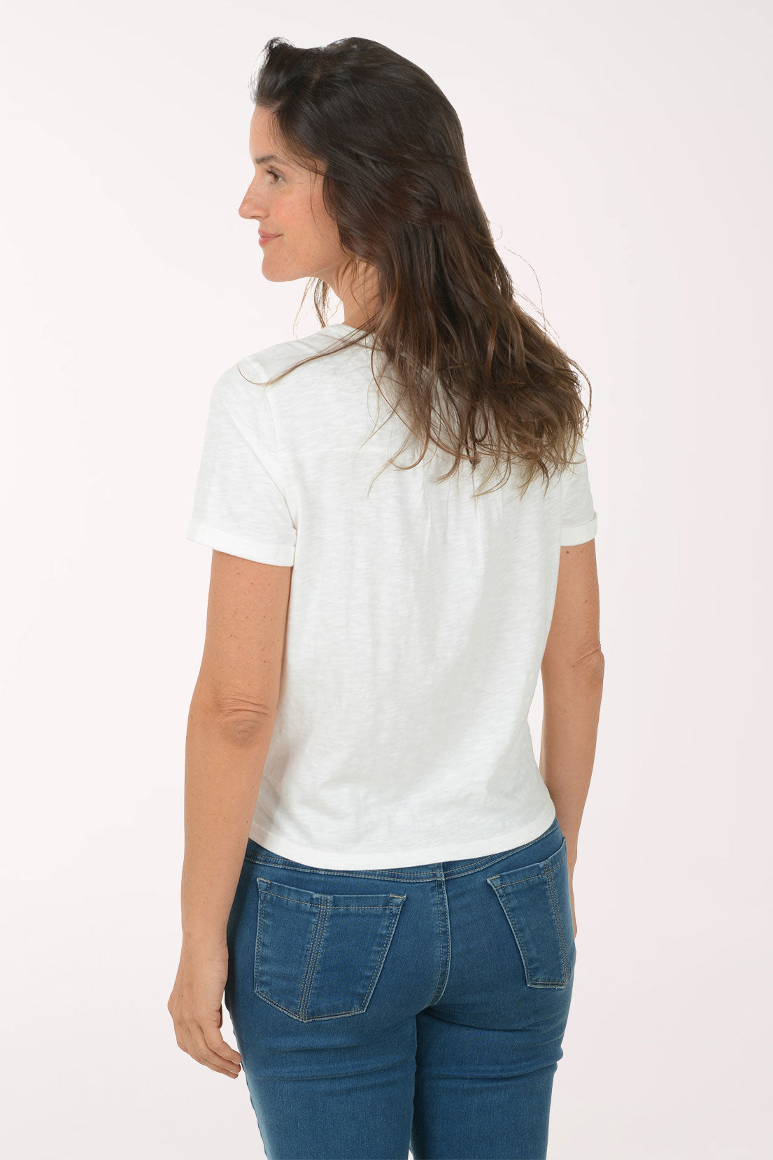 Woman wearing a white t-shirt with a tie detail and blue jeans on a white background