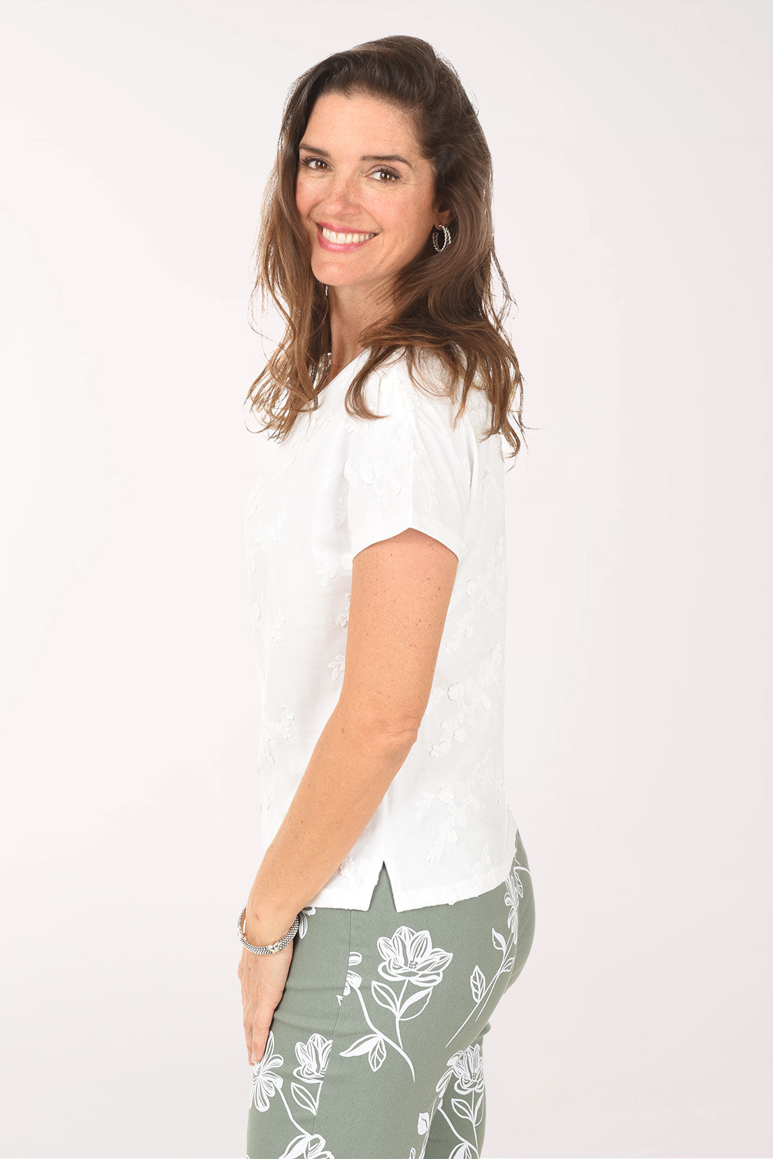 Woman wearing a white t-shirt and green floral pants on a white background