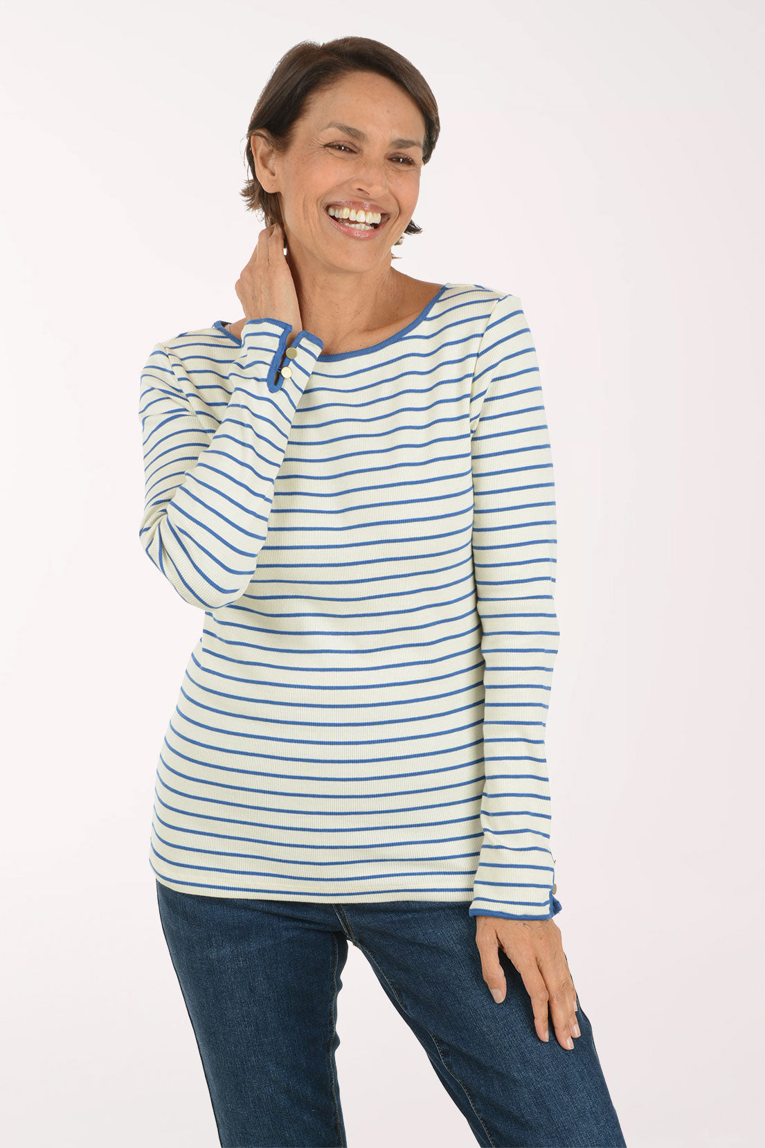 A woman modeling a long-sleeve striped top with blue and white horizontal stripes, paired with dark blue jeans, against a plain light background.
