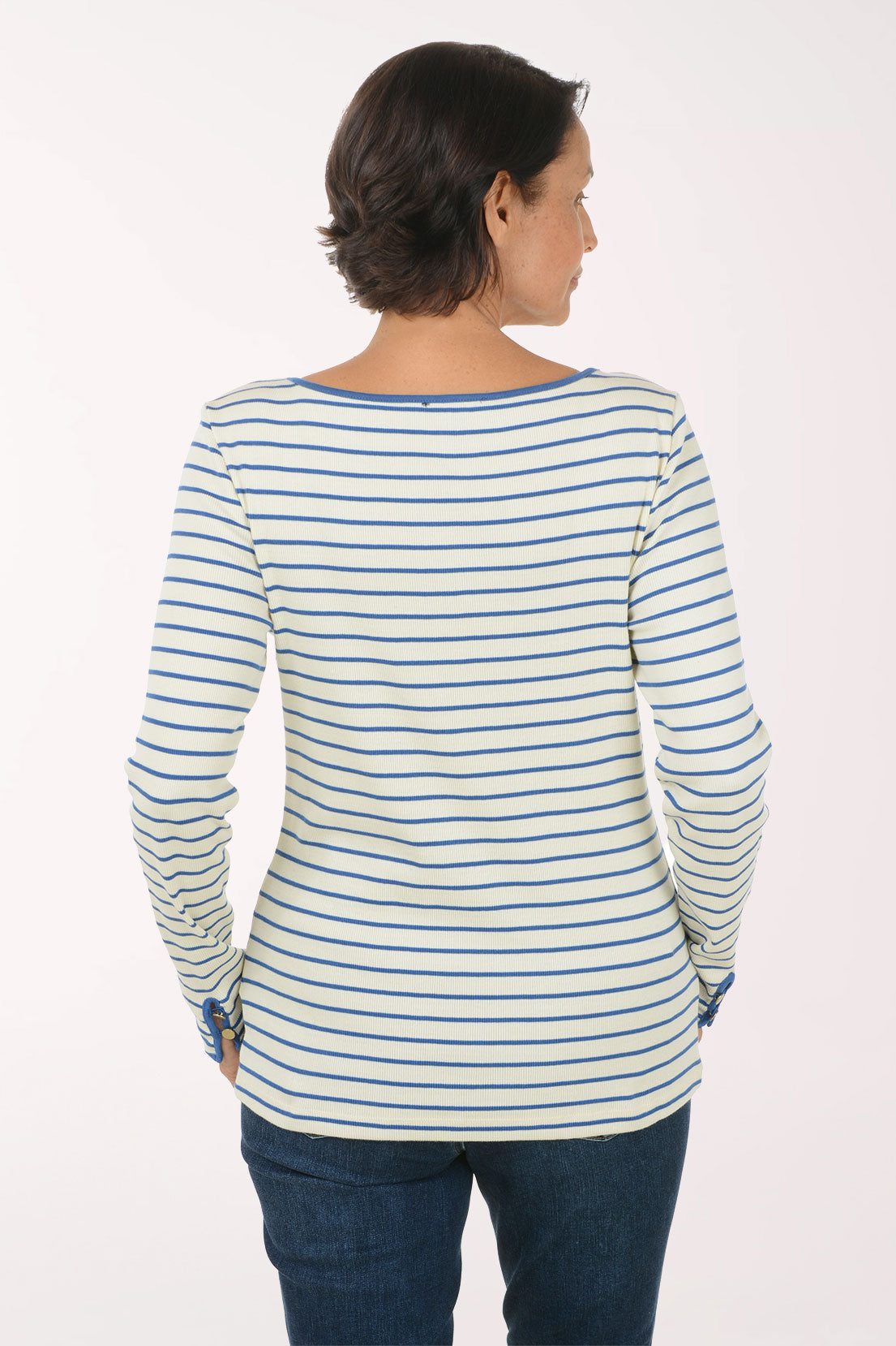 A woman modeling a long-sleeve striped top with blue and white horizontal stripes, paired with dark blue jeans, against a plain light background.