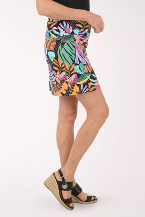 Person wearing a colorful tropical leaf patterned skirt on a white background