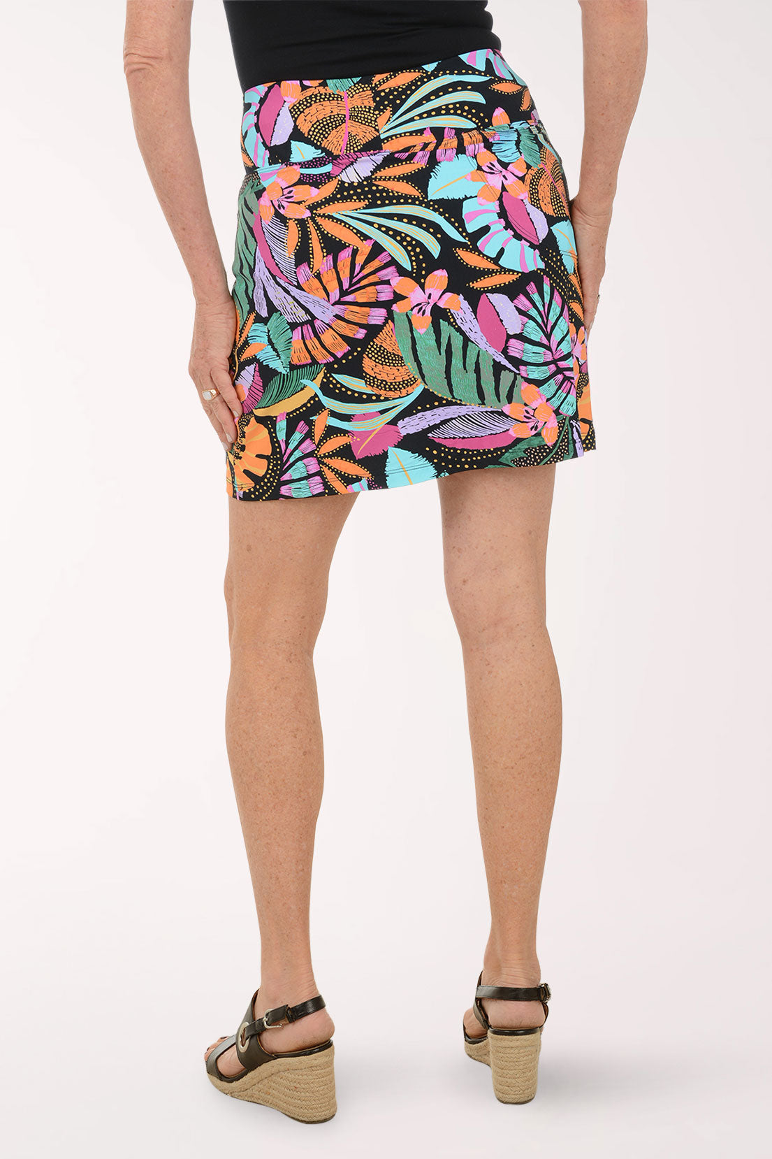 Person wearing a colorful tropical leaf patterned skirt on a white background