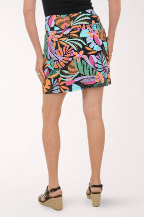 Person wearing a colorful tropical leaf patterned skirt on a white background