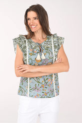 Woman wearing a floral sleeveless top with tassels on a white background