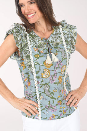 Woman wearing a floral sleeveless top with tassels on a white background