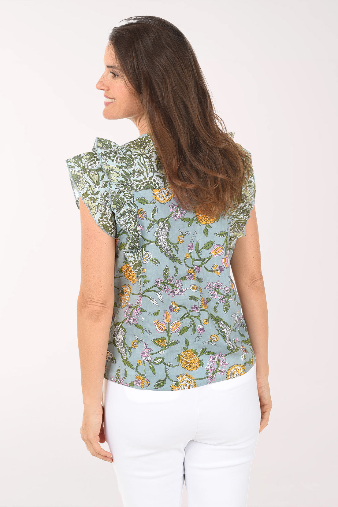 Woman wearing a floral sleeveless top with tassels on a white background