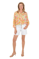 Woman wearing a colorful floral blouse and white shorts on a white background