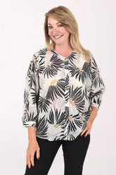Woman wearing a tropical leaf patterned blouse on a white background