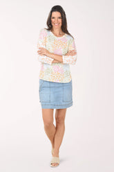 Woman wearing a floral top and denim skirt on a white background