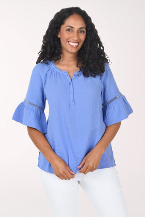 Woman wearing a blue blouse with ruffled sleeves on a white background