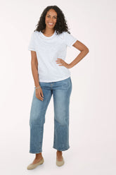 Woman wearing a white lace top and blue jeans on a white background