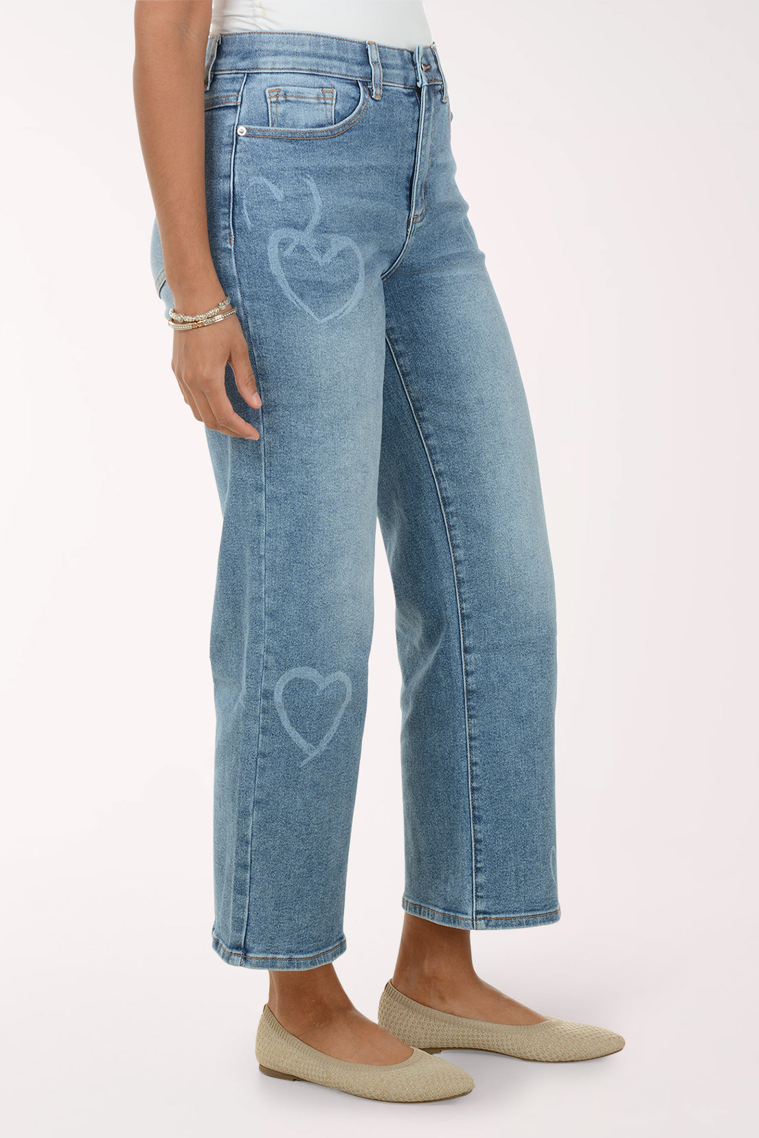 Woman wearing a white lace top and blue jeans on a white background