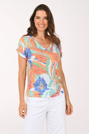 Woman wearing a colorful patterned top and white pants on a white background