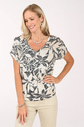 Woman wearing a patterned top and beige pants on a white background