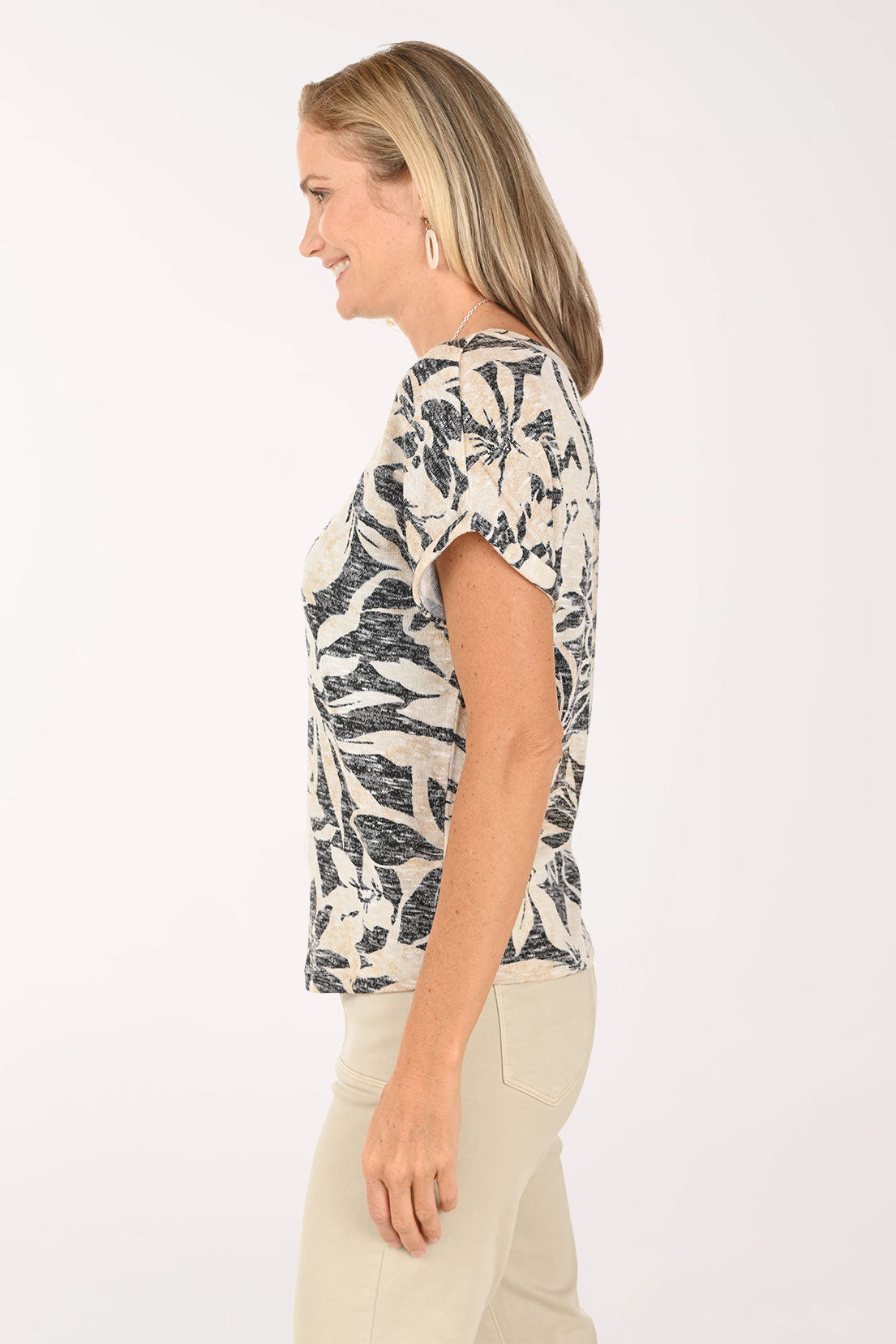 Woman wearing a patterned top and beige pants on a white background