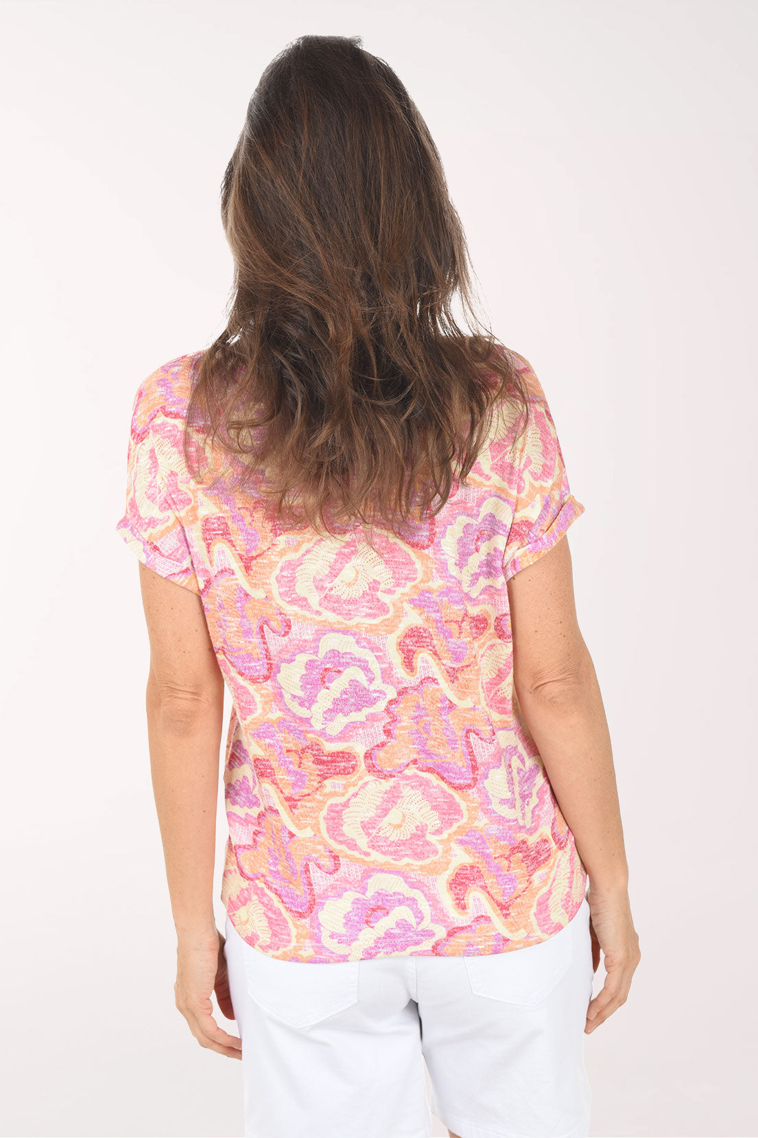 Woman wearing a pink and orange patterned top on a white background