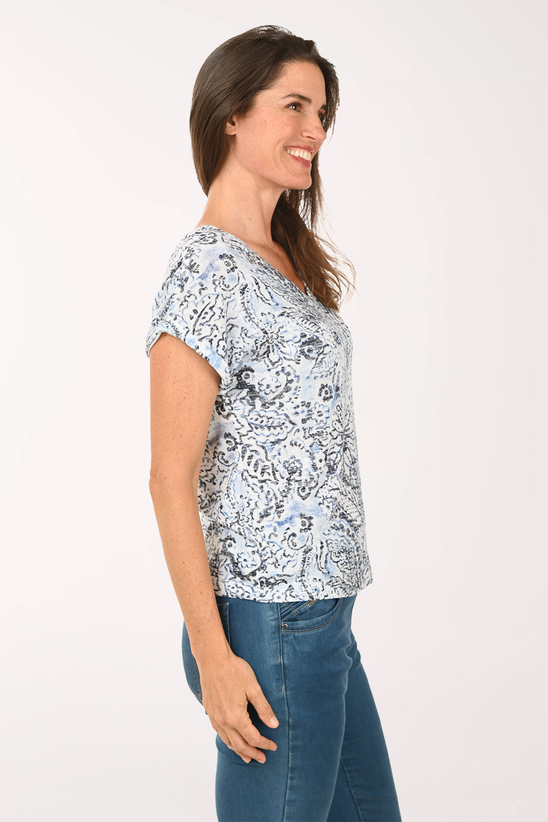 Woman wearing a floral patterned shirt and blue jeans on a white background