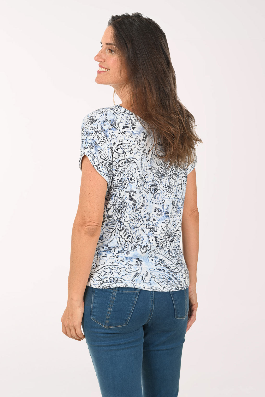 Woman wearing a floral patterned shirt and blue jeans on a white background