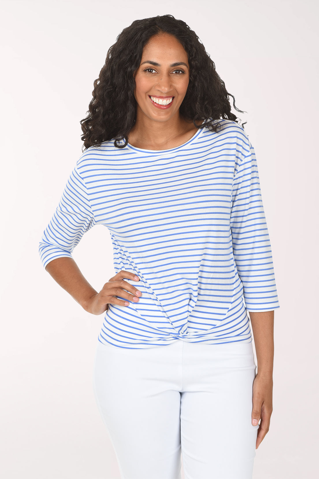 Woman wearing a blue and white striped shirt and white pants on a white background