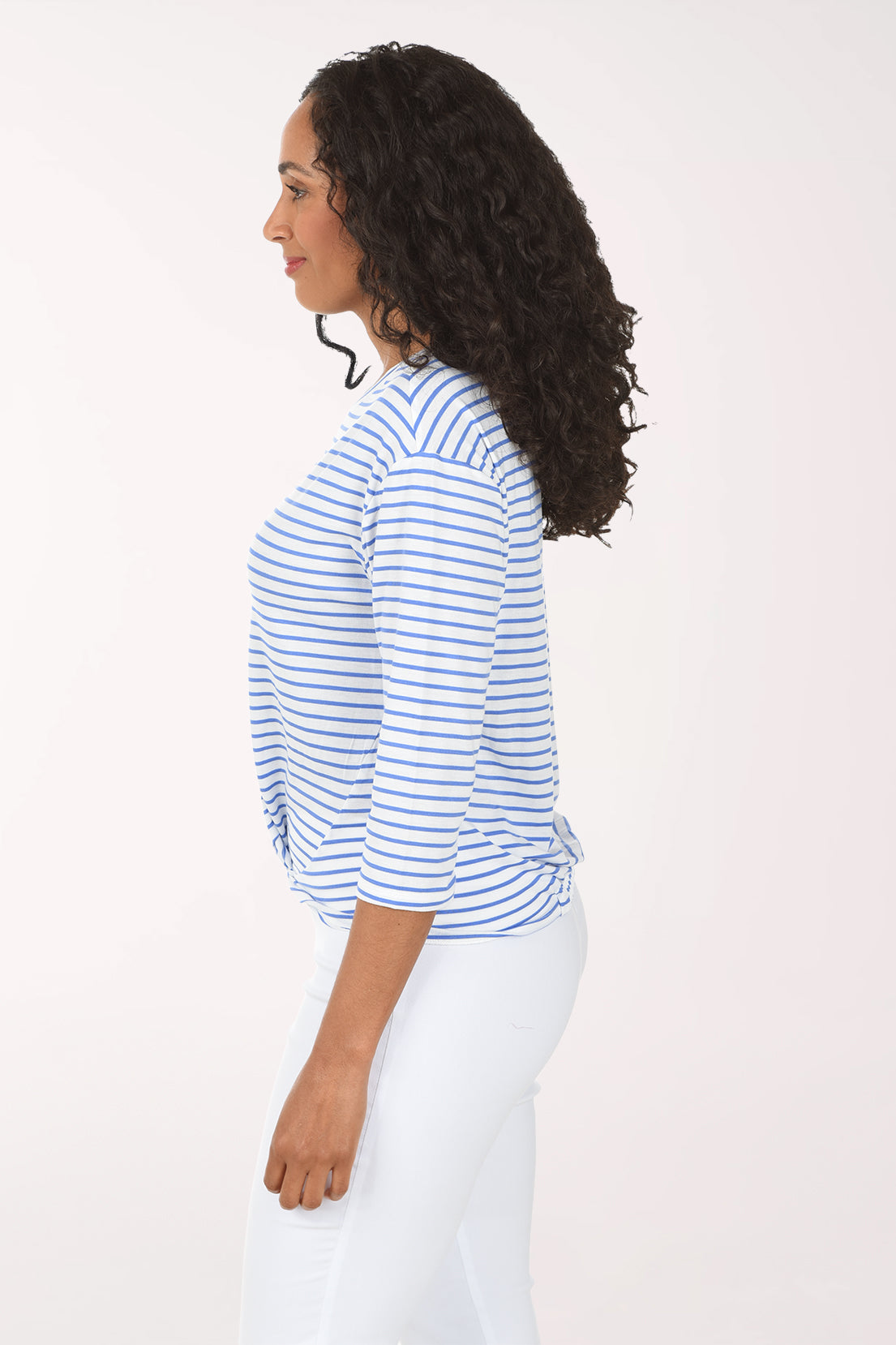 Woman wearing a blue and white striped shirt and white pants on a white background