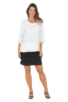 Woman wearing a white top and black skirt with white rhinestone embellishments on a white background.