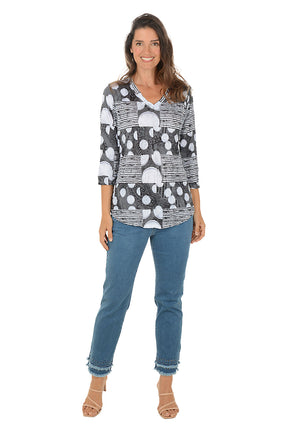 Woman wearing a patterned top and jeans on a white background.
