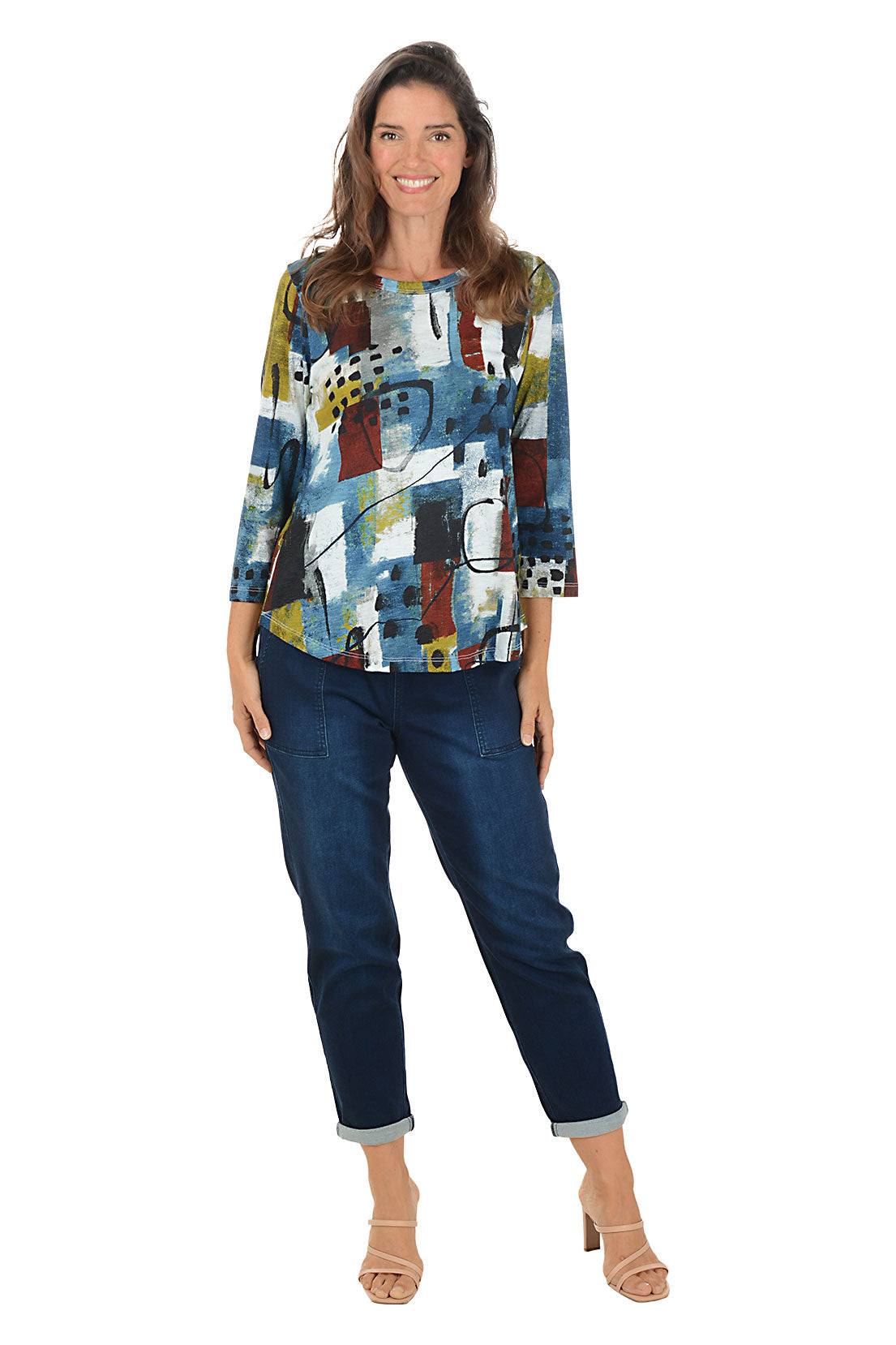 Woman wearing a colorful abstract-patterned top and blue jeans on a white background