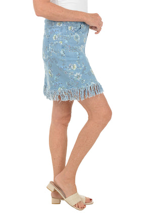 Woman wearing a blue floral skirt on a white background. Side shot.