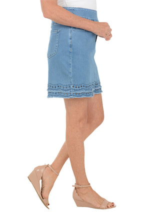 Light blue denim skirt worn by a person on a white background. Side shot.