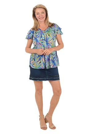 Woman wearing a colorful patterned top and denim skirt on a white background