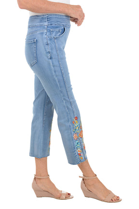 Light blue jeans with floral embroidery on a white background. Side shot.