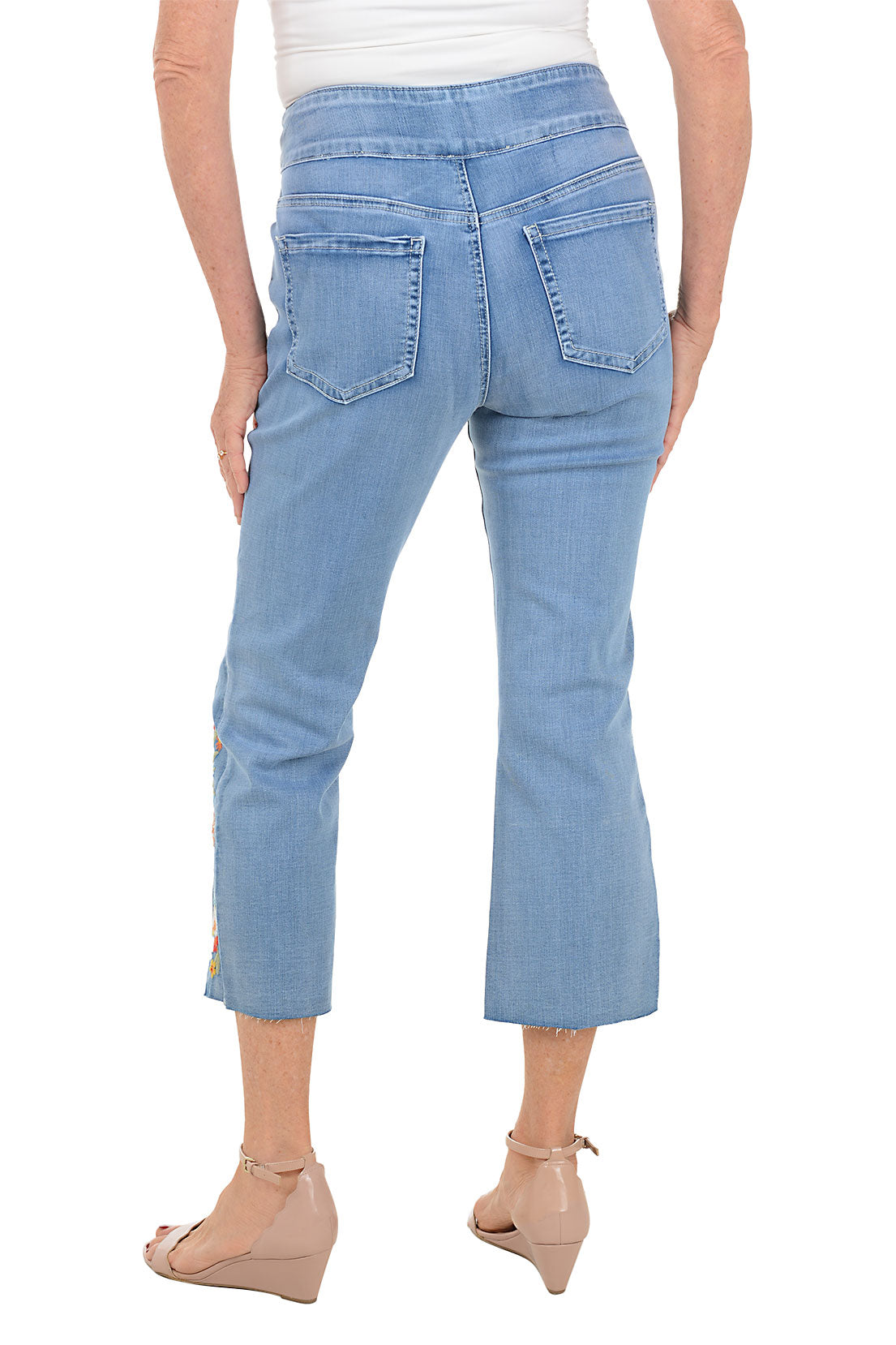 Light blue jeans with floral embroidery on a white background. Back shot.