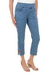 Blue jeans with colorful accents worn by a person on a white background.