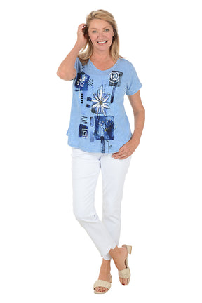 Woman wearing a blue graphic t-shirt and white pants on a white background