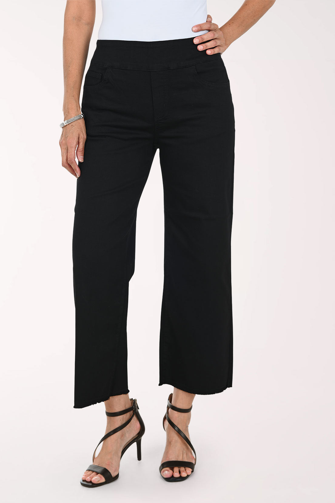 A model wearing black cropped wide-leg pants with a white top and black strappy high-heeled sandals, shown from the waist down against a plain light background.