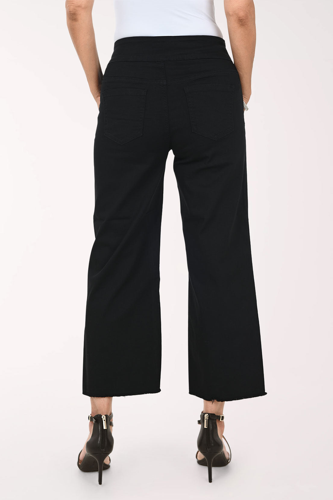 A model wearing black cropped wide-leg pants with a white top and black strappy high-heeled sandals, shown from the waist down against a plain light background.