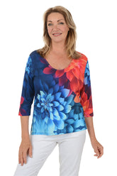 Woman wearing a colorful floral top with a white background.