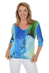 Woman wearing a colorful abstract patterned top on a white background.