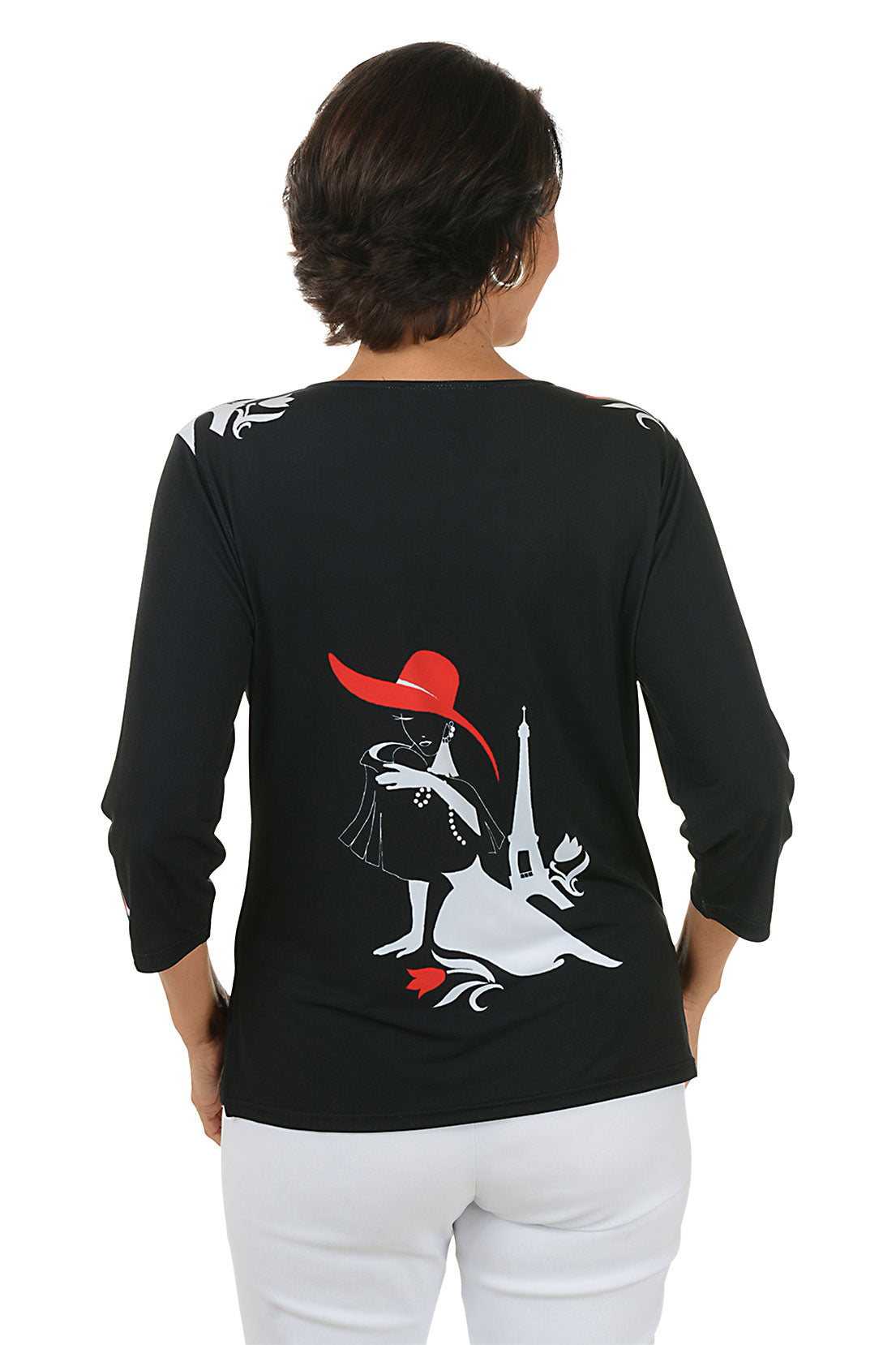 Woman wearing a black top with a graphic design of a woman in a red hat and white dress. Back shot.