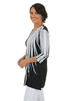 Woman wearing a black and white patterned top on a white background. Side shot.