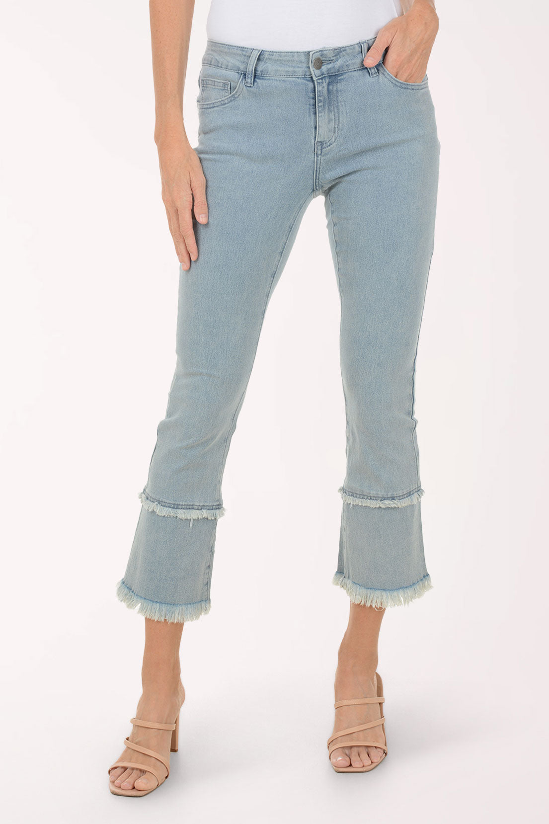 Light blue jeans with frayed hems worn by a person on a white background
