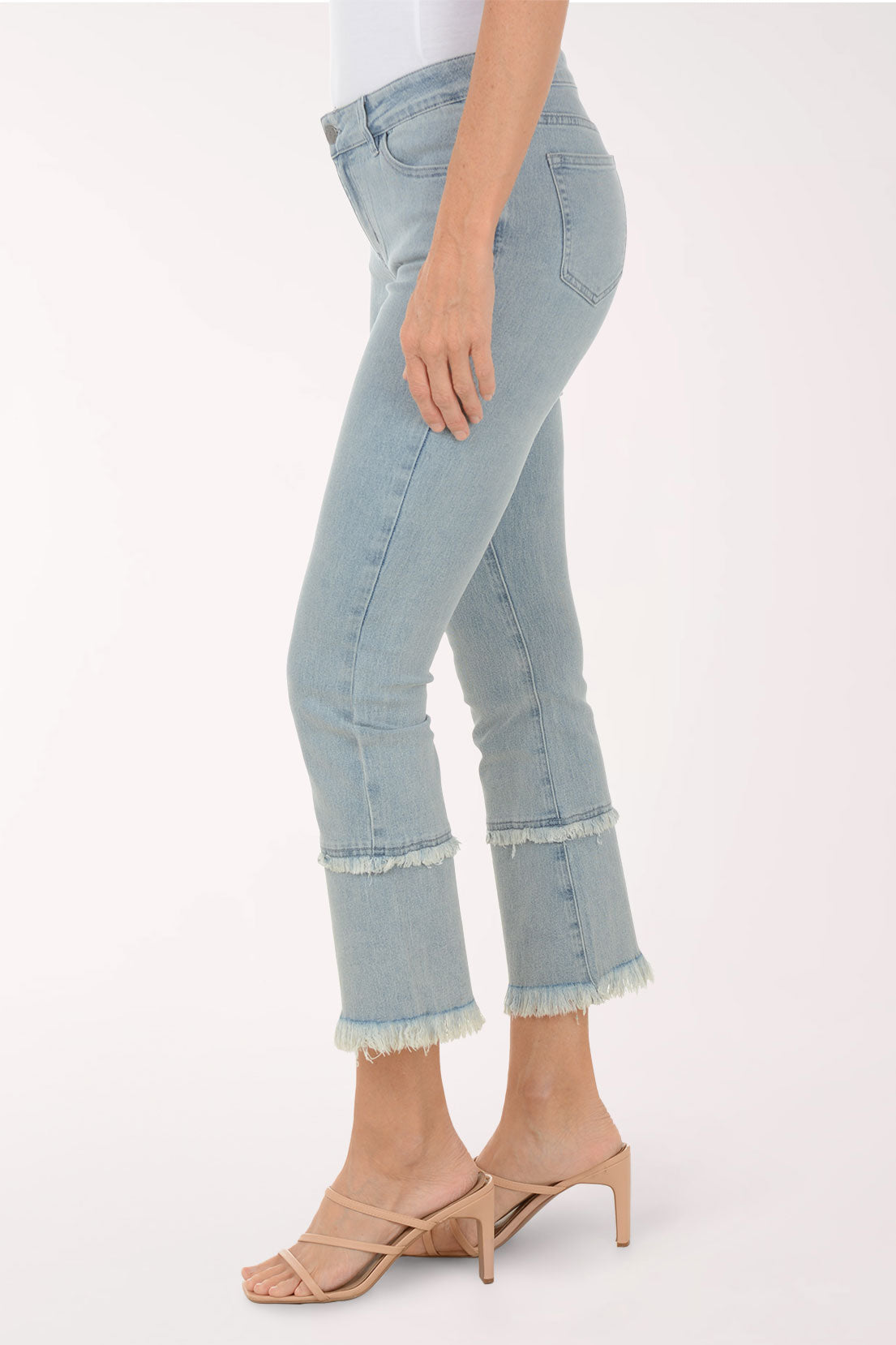Light blue jeans with frayed hems worn by a person on a white background