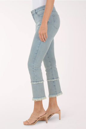 Light blue jeans with frayed hems worn by a person on a white background