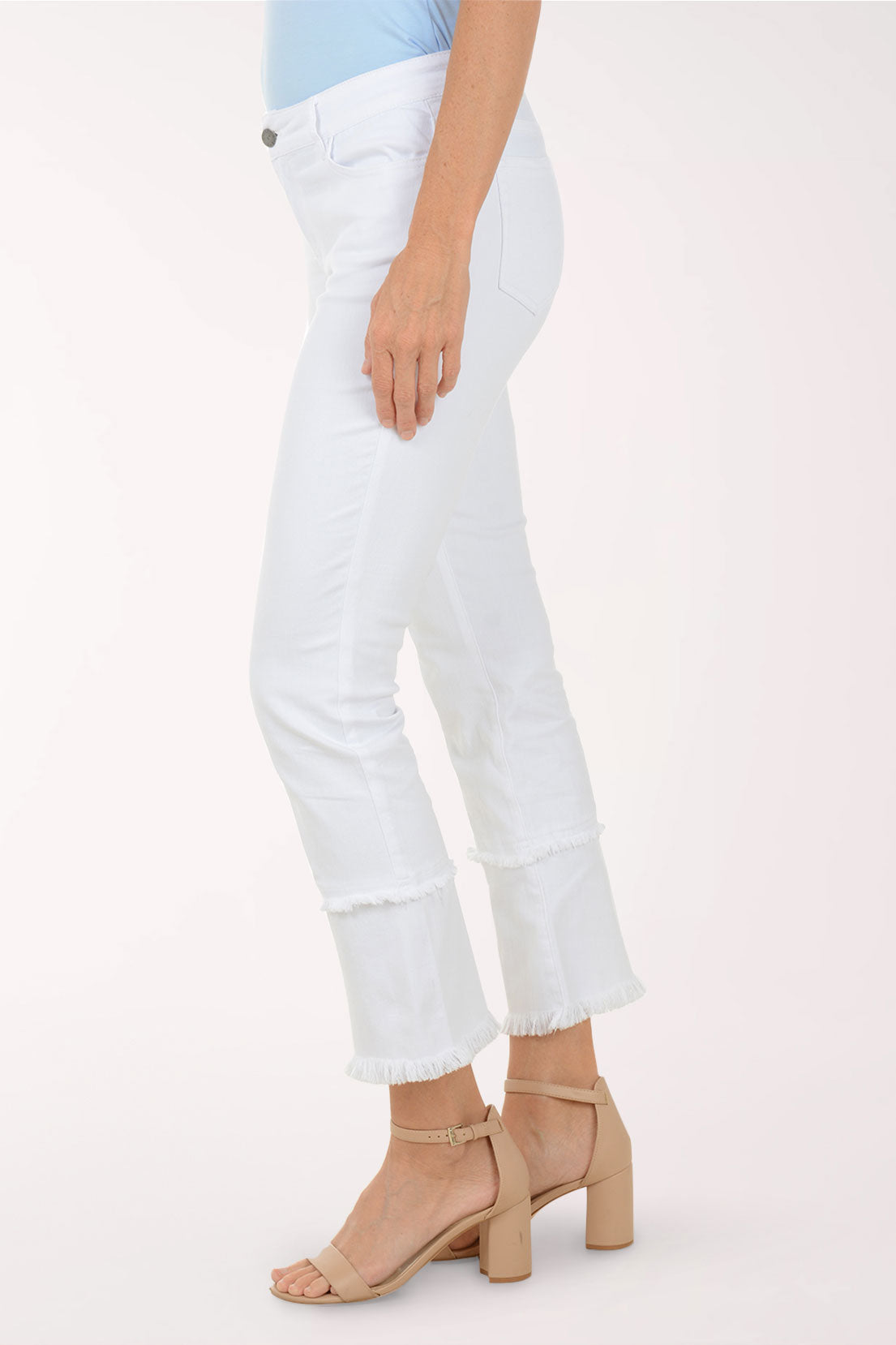 Person wearing white jeans and beige sandals on a light background