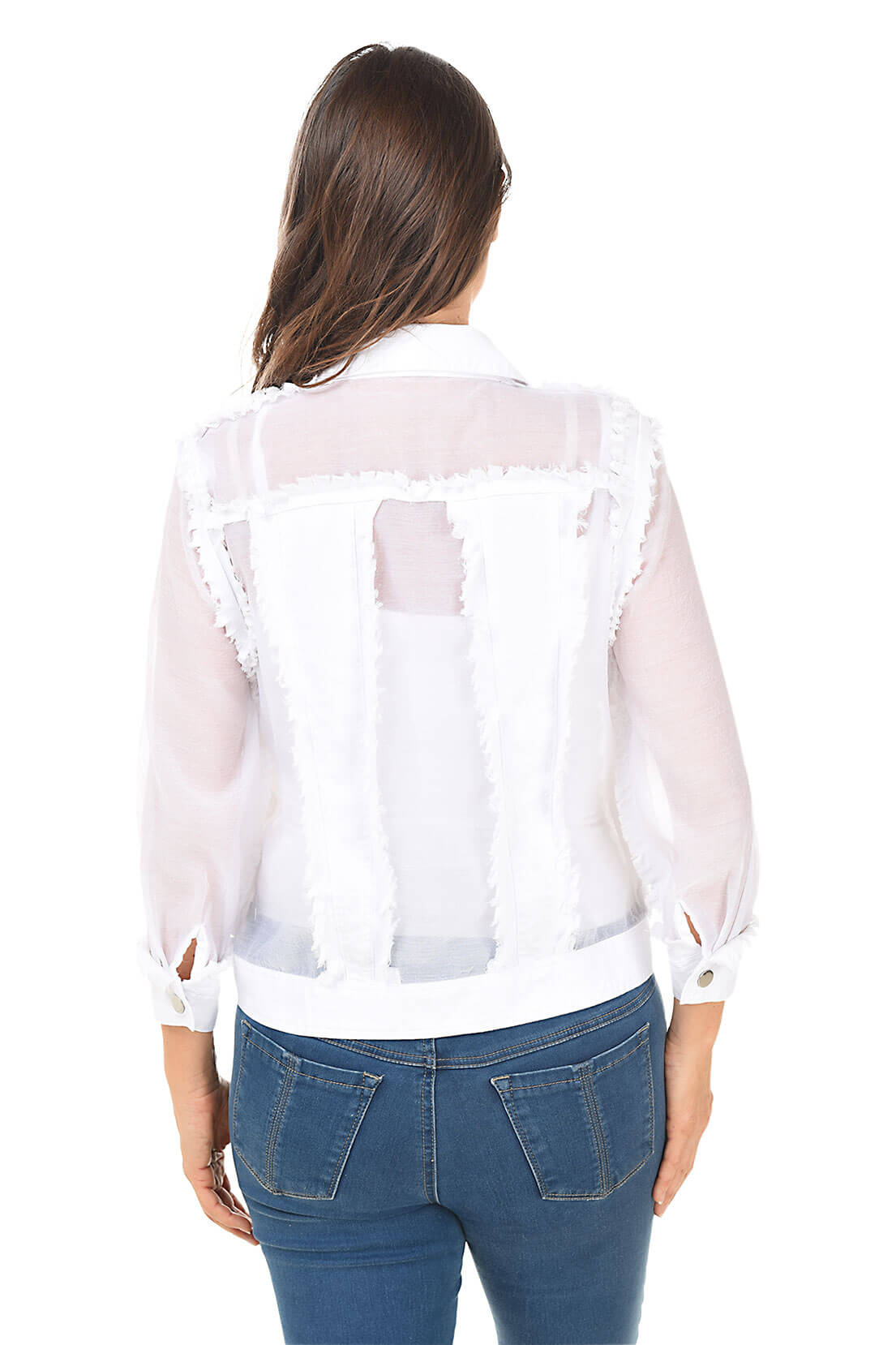 Woman wearing a sheer white blouse over a white shirt with blue jeans on a white background