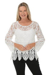 Woman wearing a white lace top on a white background.